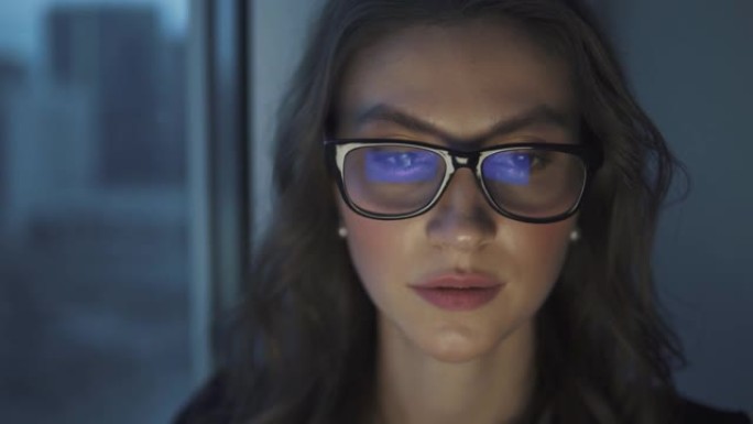 带眼镜的显示器的反射。在笔记本电脑上工作的迷人年轻女孩