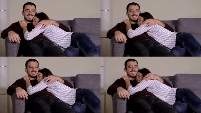 沙发上的年轻夫妇拥抱。爱情放松的夫妇在家里