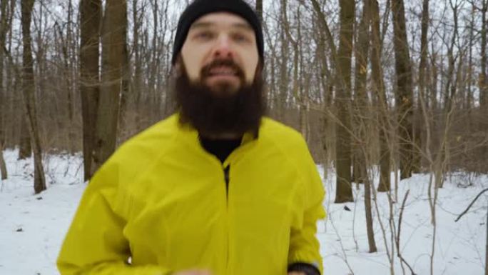 在白雪皑皑的冬季森林中，有胡子的运动员朝着相机奔跑的手持镜头