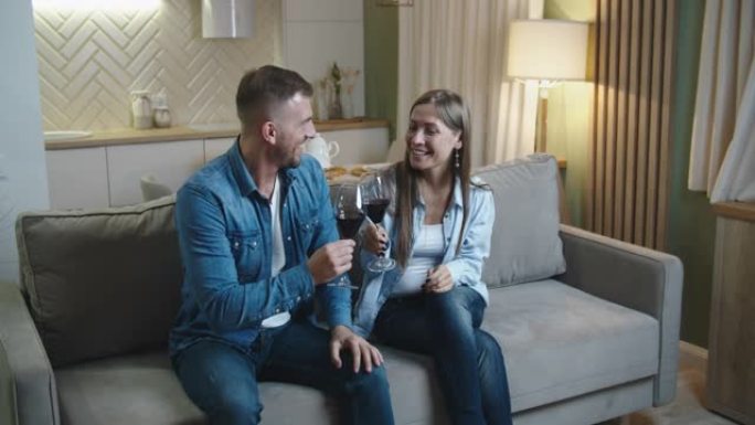 夫妻俩在家里的沙发上喝红酒，看电视。晚上回家。