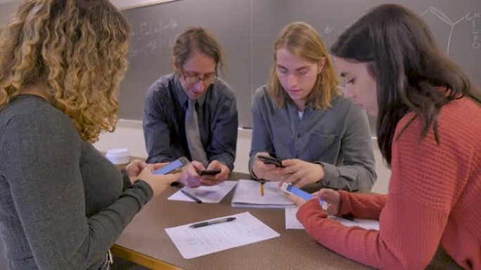 老师和三名学生都在教室里使用手机