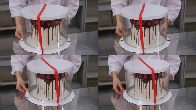 一个女孩在白色蛋糕盒上绑红丝带的特写镜头。