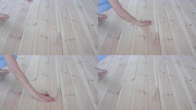 环保地板-赤脚的女人抚摸温暖的木地板特写。