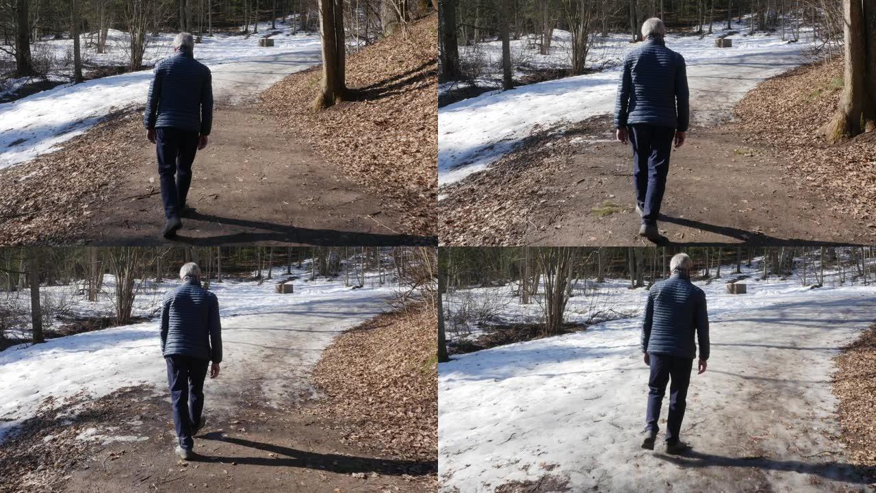 老人在阳光明媚的日子在春天的公园里散步