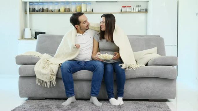 一个男人和他的妻子坐在盖着毯子的沙发上