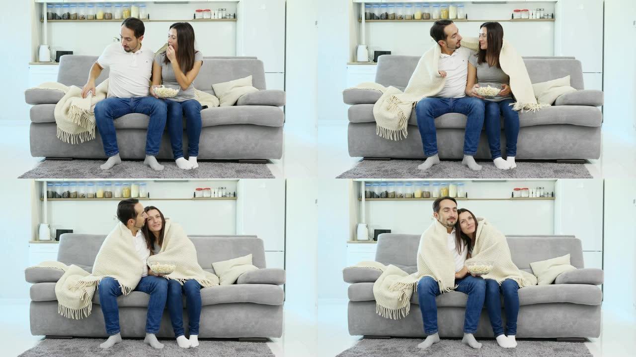 一个男人和他的妻子坐在盖着毯子的沙发上
