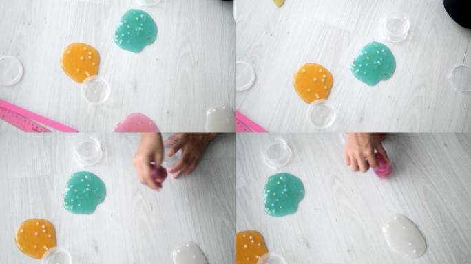 女孩的手在家里坐在地板上玩粘液或玩具粘土，生活方式的概念。
