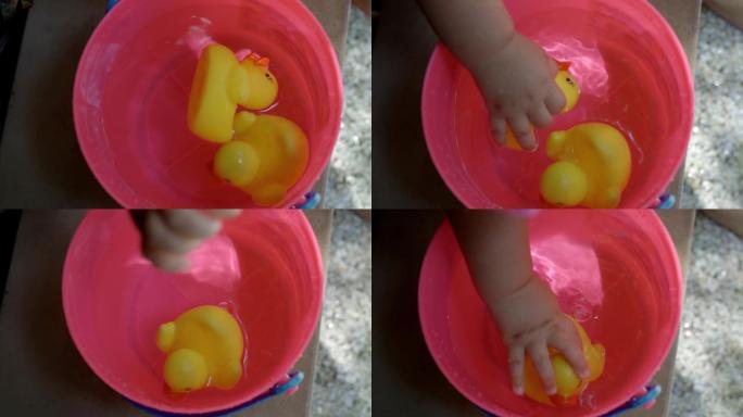 一只黄色塑料鸭子漂浮在粉红色婴儿桶中的美丽镜头，孩子的手在慢动作中拍摄鸭子-视频