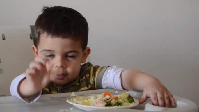 脾气暴躁的两岁男孩玩食物，拒绝吃东西。