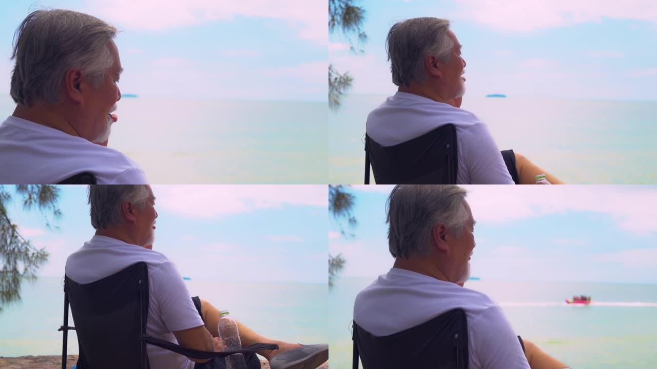 亚洲老人愉快地坐在海滩上放松的一天。