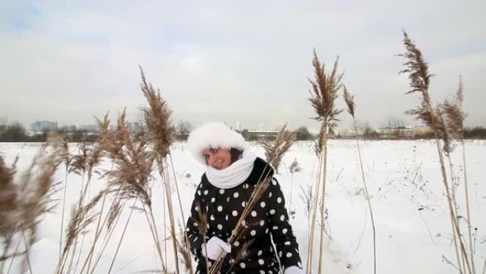 女孩走过冬天的荒原。坐在高大的干草中间。周围有很多雪。