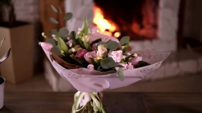 花大师班结束后，粉红色装饰纸上的美丽柔和的花束站在灰色桌子上的茎上。花卉装饰设计理念。背景上的壁炉