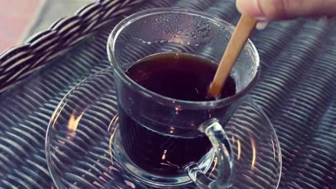 勺子搅拌在玻璃杯中混合热黑咖啡饮料
