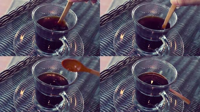 勺子搅拌在玻璃杯中混合热黑咖啡饮料