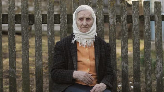 一位老奶奶坐在村子里的长椅上。