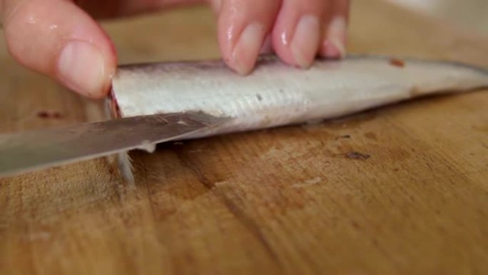 厨师手在砧板上准备生鱼。特写。女人在厨房里煮生冷冻鱼
