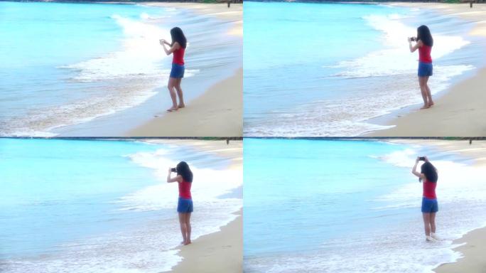 缓慢的运动女性正在玩电话，而蓝色的海浪正席卷海滩。