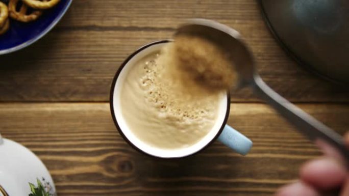 将汤匙中的蔗糖倒入加牛奶的咖啡中