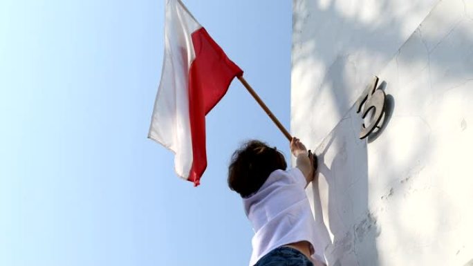 这个男孩正在悬挂一面旗帜。波兰5月3日国庆日，宪法日