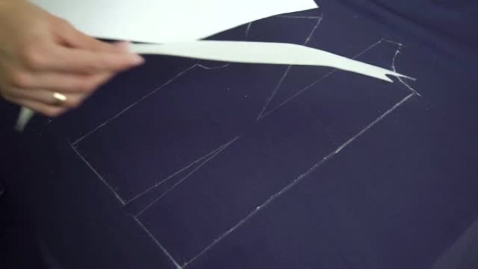 女裁缝手从织物上取下纸模板的特写