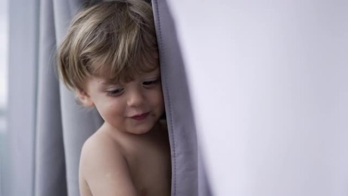 躲在窗帘后面的婴儿蹒跚学步的男孩