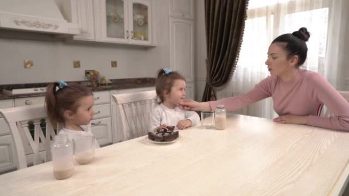 小双胞胎吃健康营养甜点并在厨房与母亲交谈的演示视频。短暂的午休时间