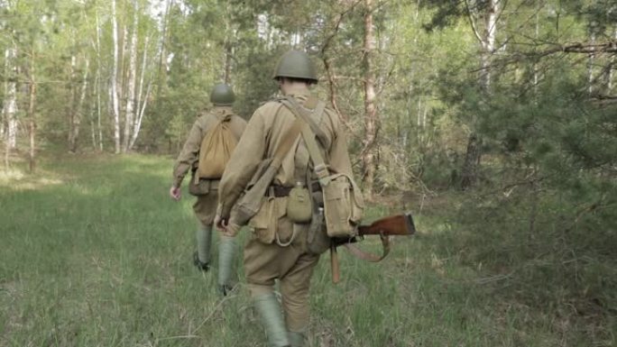 俄罗斯苏联步兵红军士兵在夏季沿着森林路行走。一群士兵在森林中行进