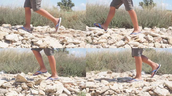 穿着石板的男人的脚在岩石上行走的特写镜头，晴天的慢动作视频