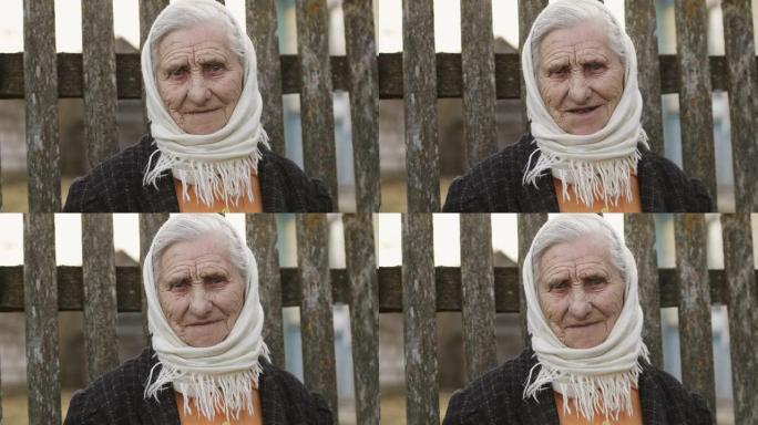 一位老女人的肖像，在旧篱笆的背景上，围巾上有深深的皱纹。