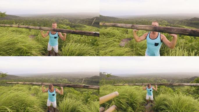 运动员男子在热带丘陵和高地景观上举起沉重的木杆。热带地区户外健身房时，健美运动员用木制杠铃训练新闻练