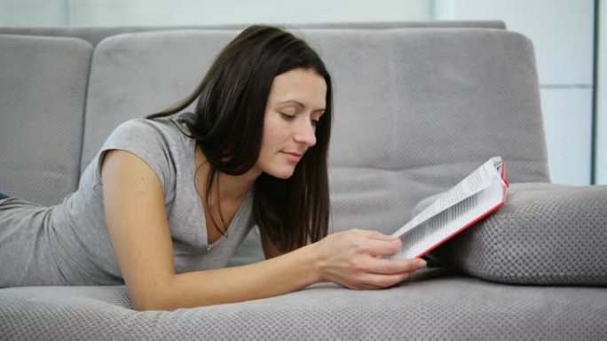 一个女人坐在沙发上读一本红皮书