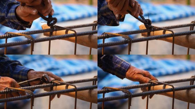 近距离施工工人的手使用钳子工具和铁丝编织金属棒，以在混凝土浇筑之前固定钢筋。建筑施工和行业概念。运动