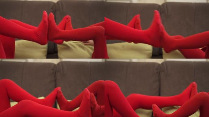 两个穿着红色紧身衣的小女孩在床上玩耍，互相推腿