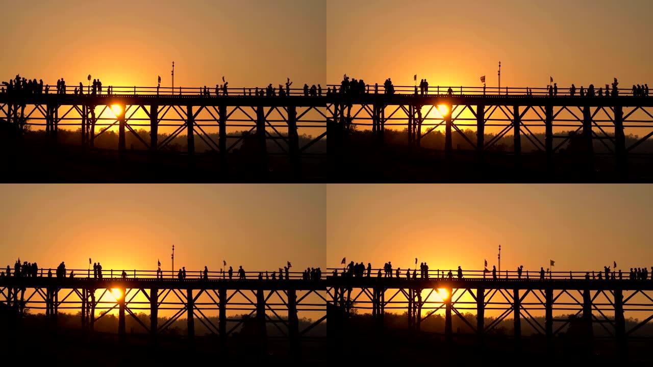 太阳下山时，游客在木桥上行走，