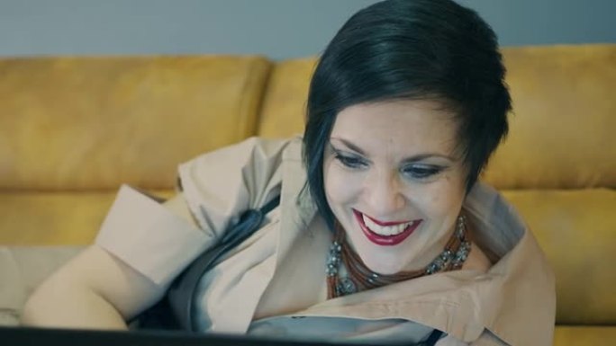 快乐的女性脸看着笔记本电脑屏幕特写。女人在工作和与笔记本电脑交流时的情绪。女人的脸特写