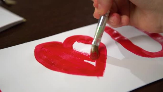 手绘我爱你的心用白纸上的红色颜料。制作情人节贺卡的特写。