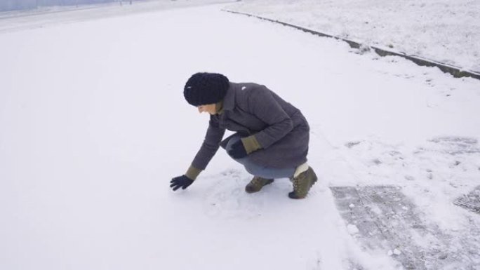 快乐的女人享受第一个雪滚雪球堆雪人