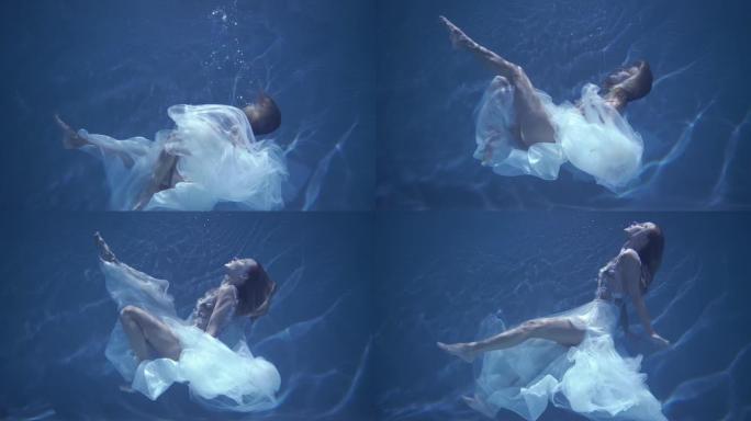 穿着白色连衣裙的长发女孩漂浮在水下