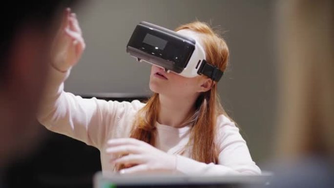 相机从带有代码的笔记本电脑倾斜到年轻女子，在办公室进行VR应用测试时在开发人员附近探索虚拟现实