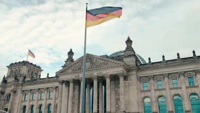 慢动作德国国旗在首都柏林市中心联邦议院议会大楼的背景下。在蓝色宁静的天空的背景下