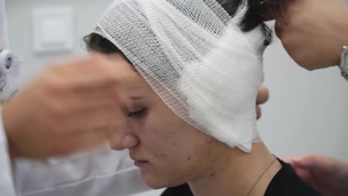 耳部手术后，医生在诊所对头部患者进行绷带包扎