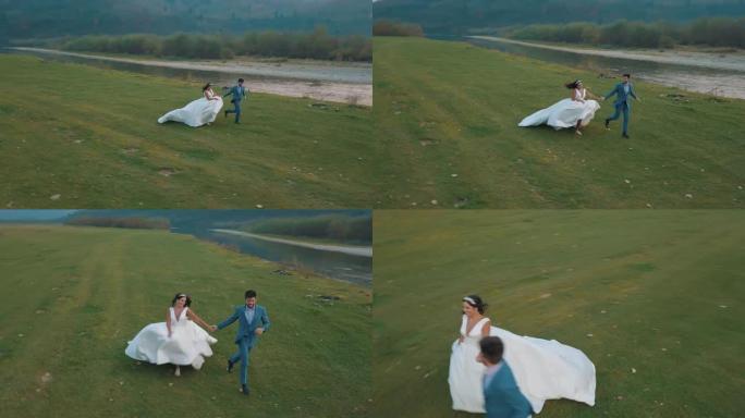 结婚夫妇在山河附近奔跑。新郎和新娘。Arial视图
