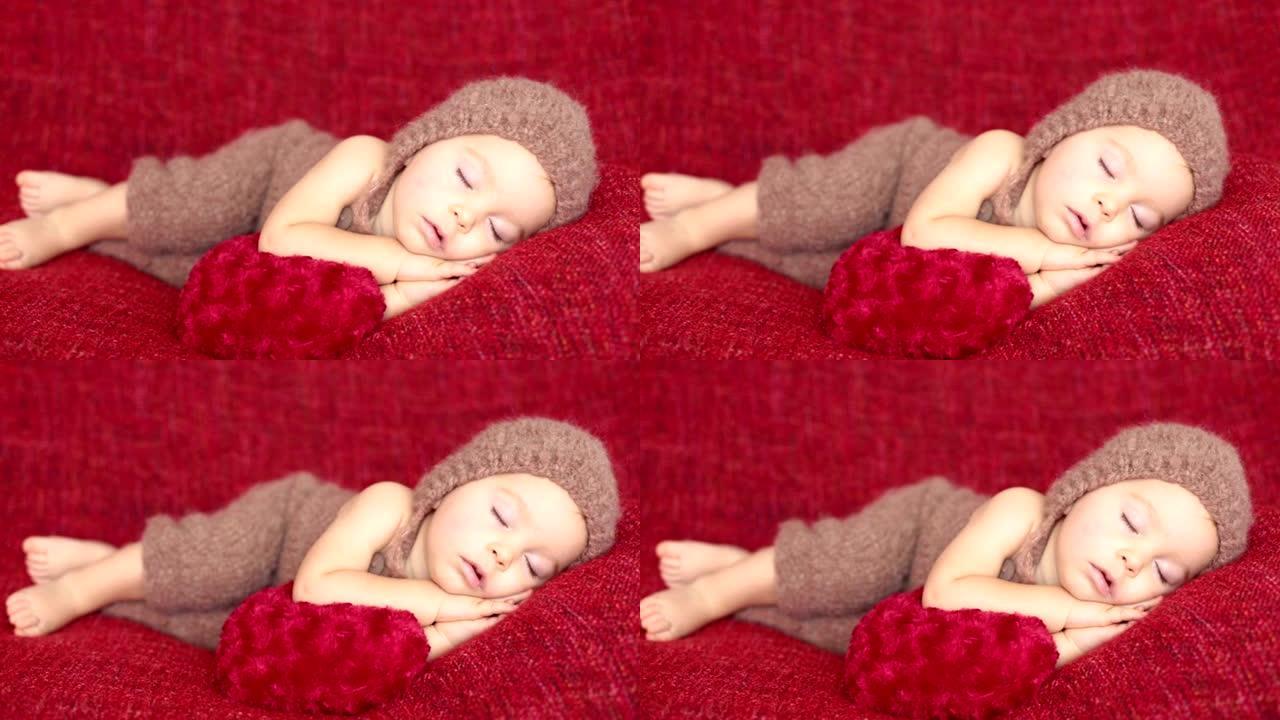 可爱的蹒跚学步的小男孩，带着心形玩具睡觉，可爱的针织衣服，孤僻