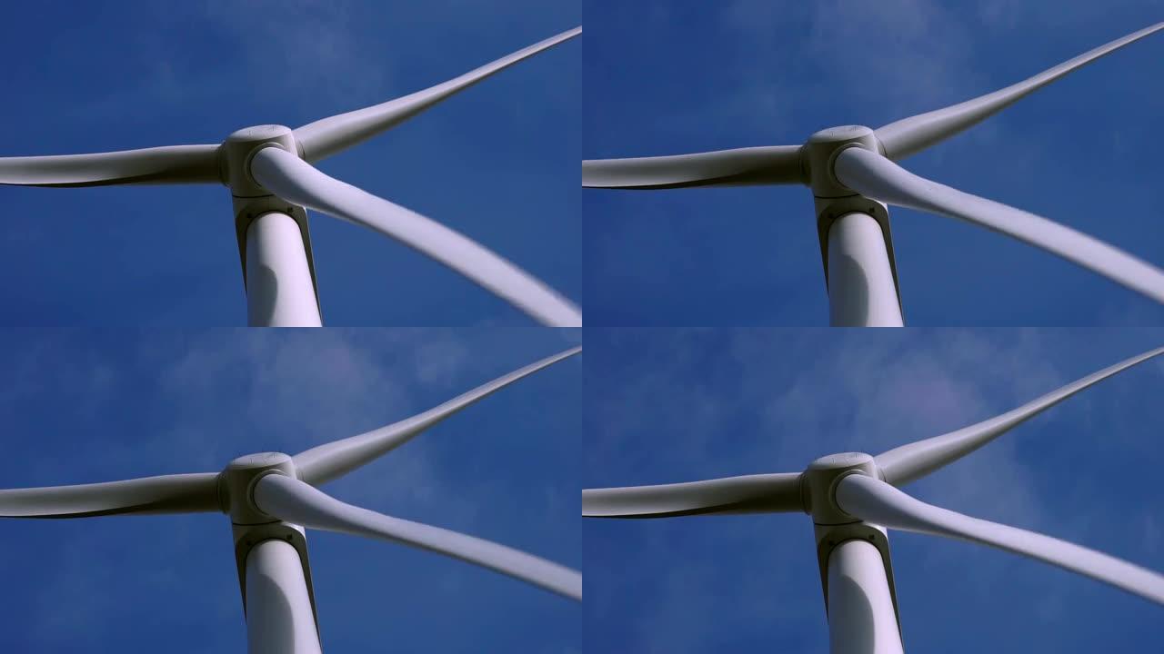在蓝天背景下旋转的风力涡轮机转子叶片的特写
