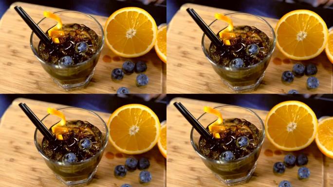 酒杯上的酒精鸡尾酒桌上有橙色，冰和蓝莓