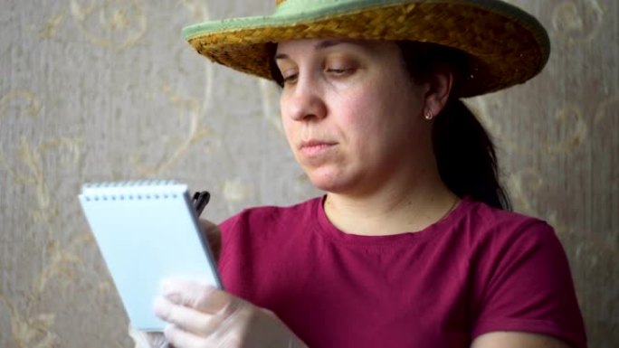 一个戴着牛仔帽的女人在墙上贴着墙纸，写在笔记本上