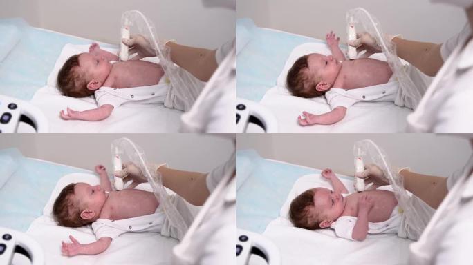 一名女医生在诊所使用现代医疗设备对新生男孩的软组织和内脏进行超声检查。儿科和儿童发育监测