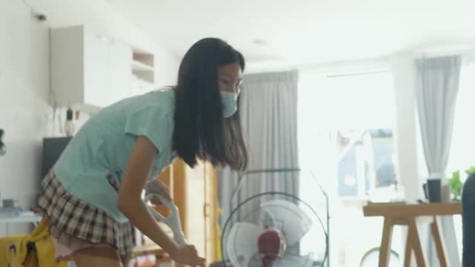 亚洲女孩戴着口罩，在家打扫卫生，生活方式理念。