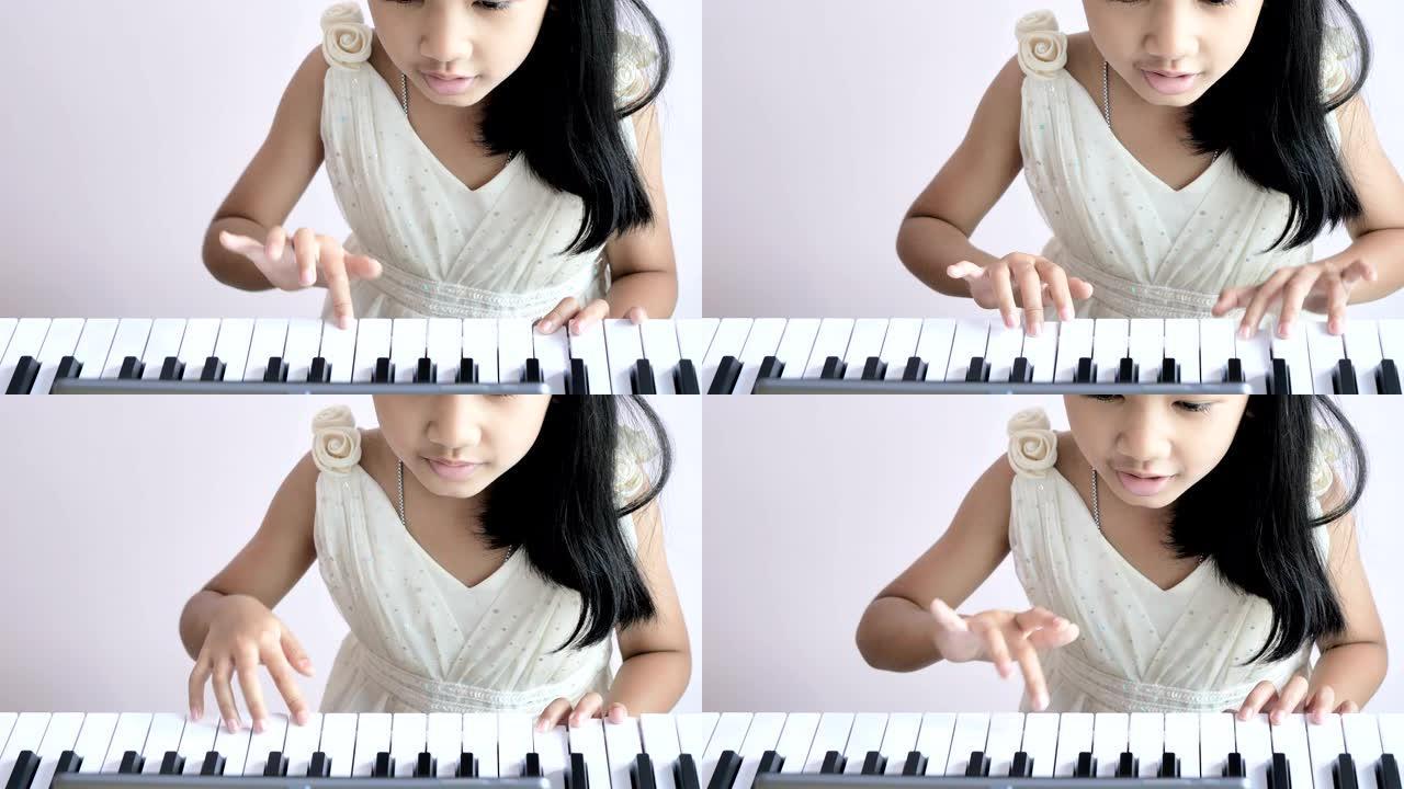 穿着白色连衣裙弹钢琴的特写女孩