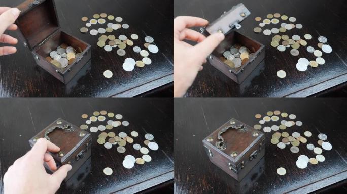 旧棕色棺材里的古董旧硬币。手正在用钱币关闭旧棺材